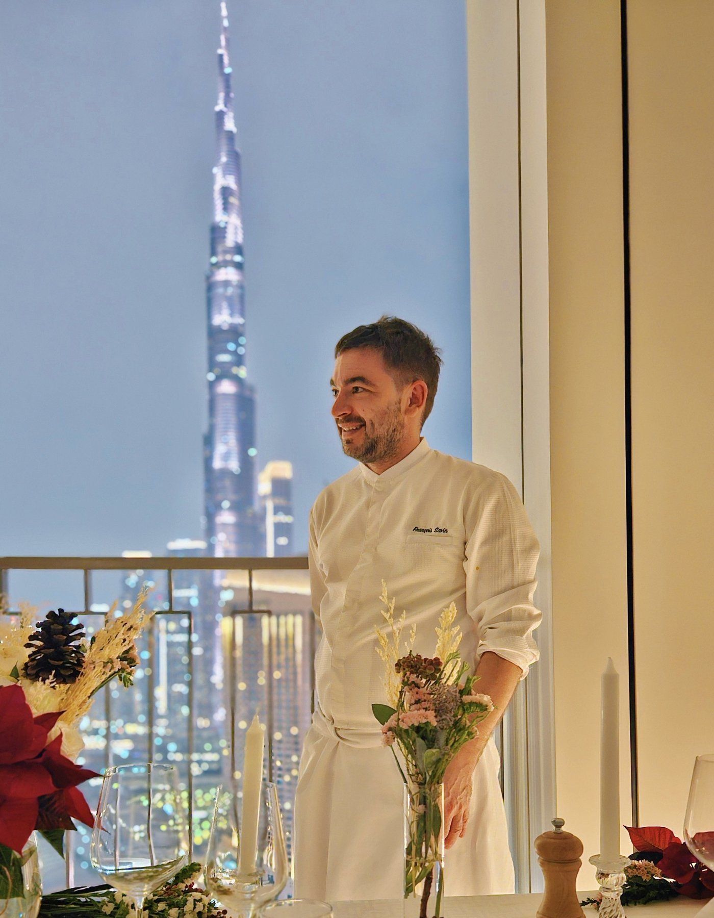 Chef François Savin at a table beneath the Dubai skyline.