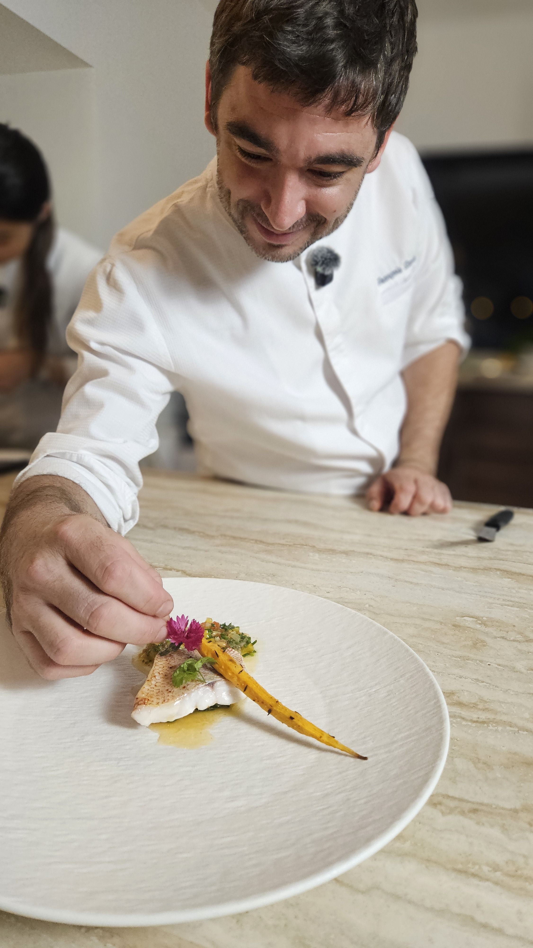 The chef finishing a plate with a glazed baby carrot.