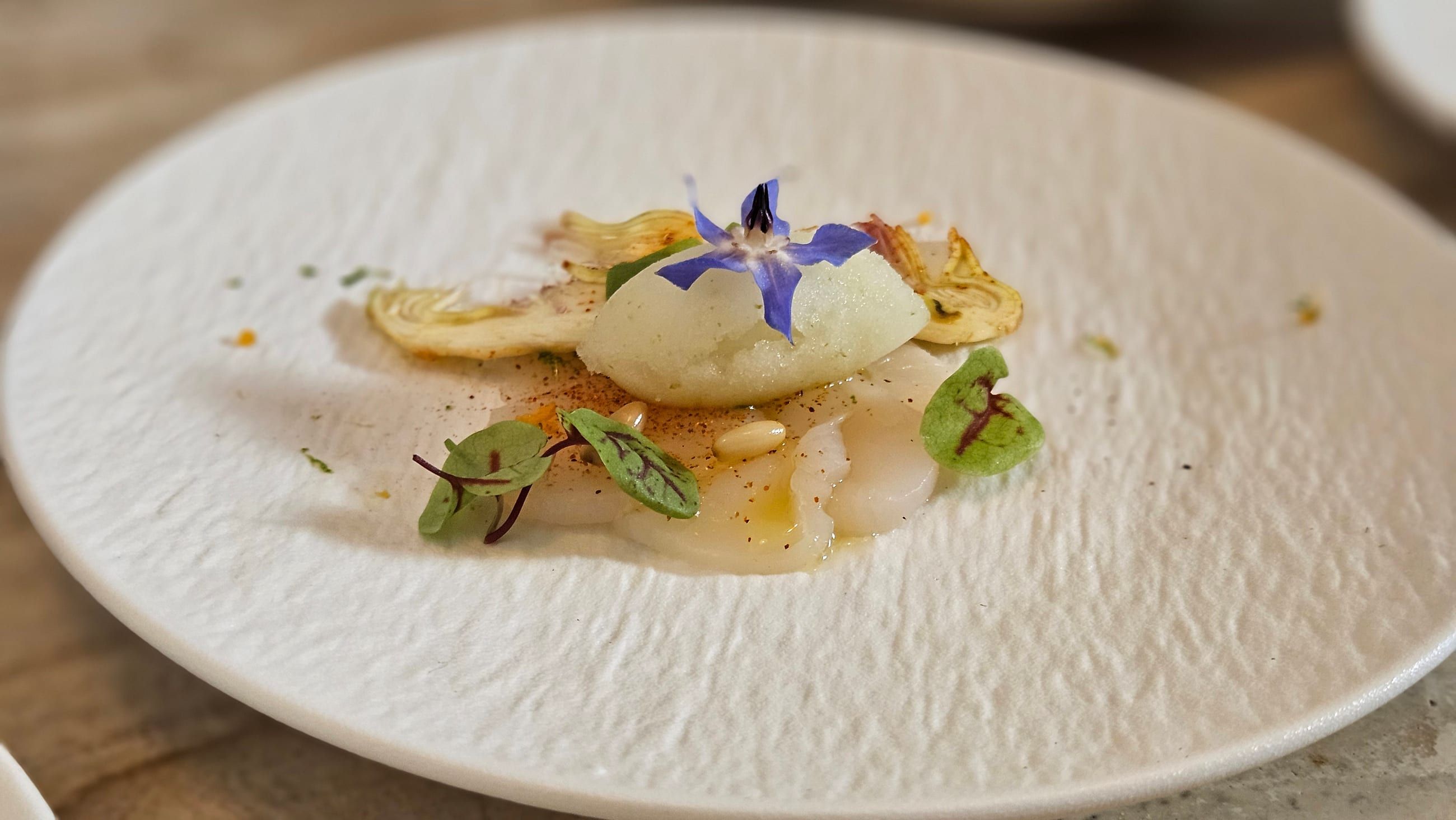 An artichoke carpaccio with shaved parmesan and pine nuts.