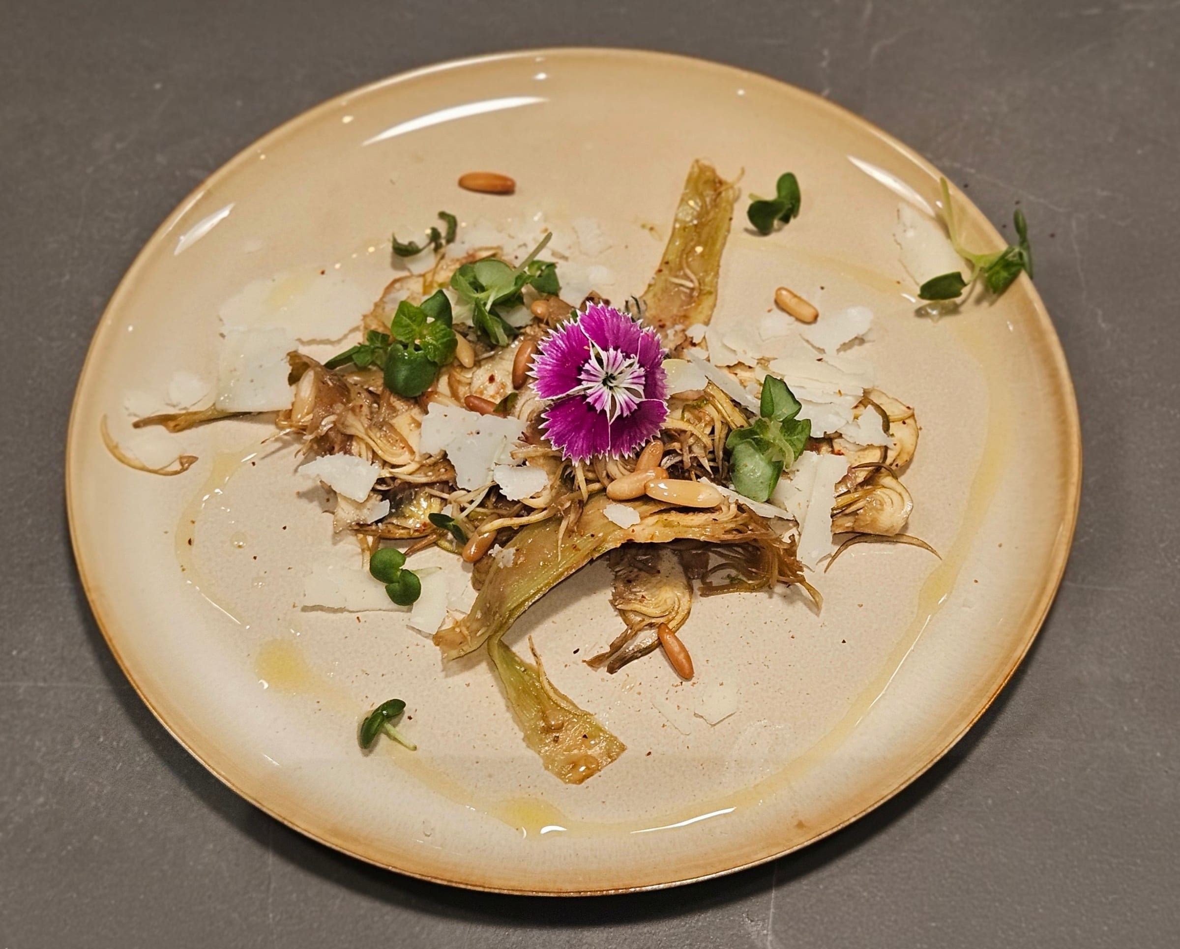An artichoke carpaccio with shaved parmesan and pine nuts.
