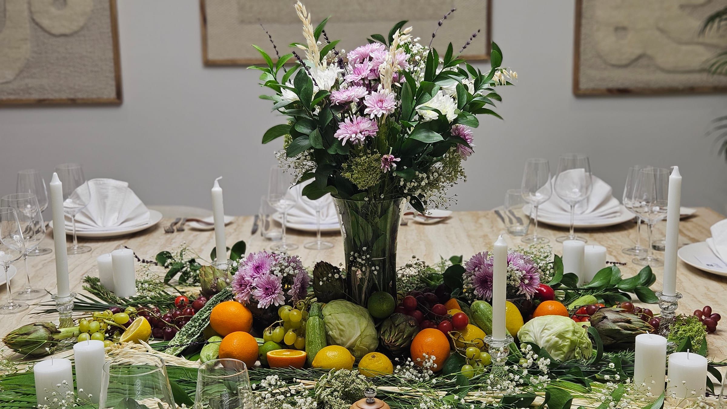 A long Dubai dining table dressed for the evening, candles and a runner of flowers and fruit.