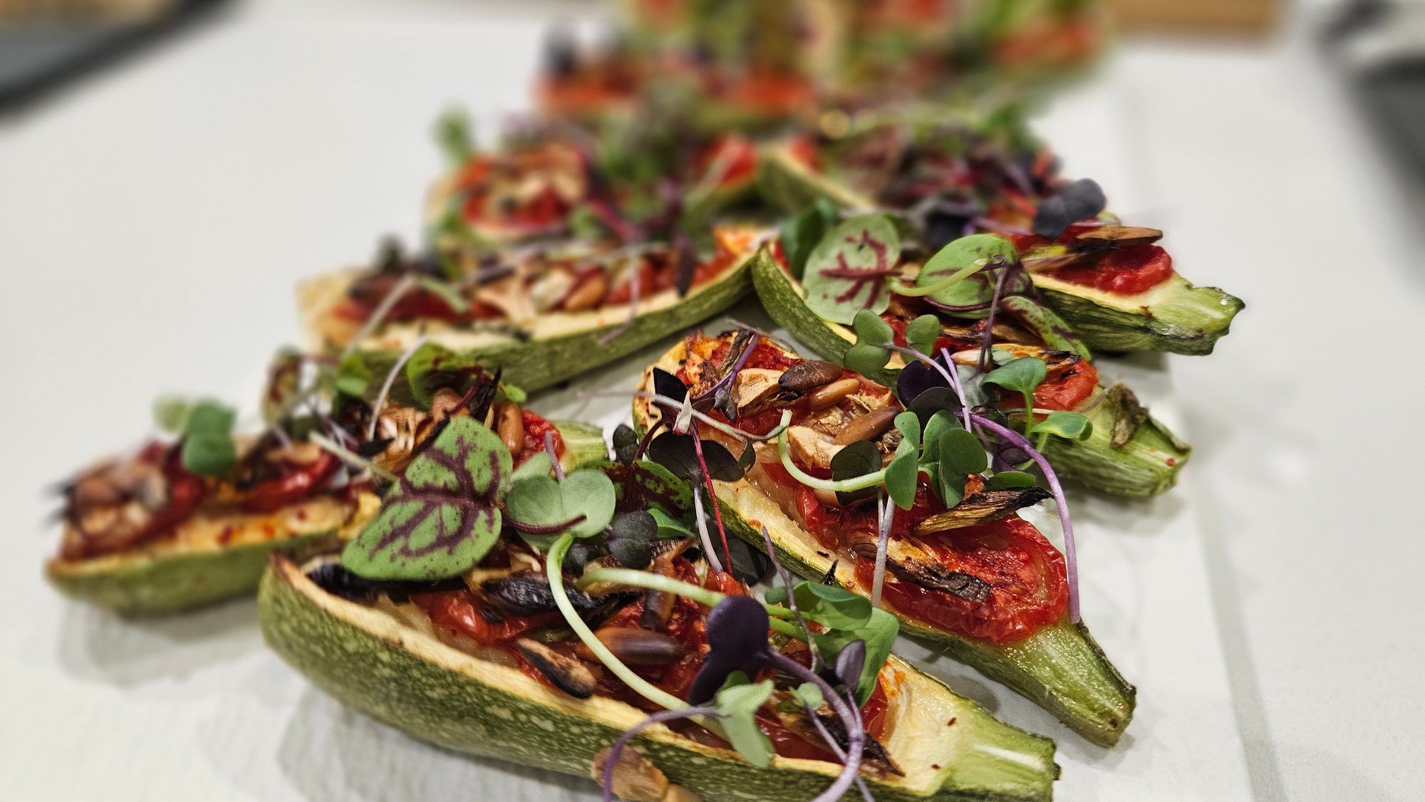 Roasted stuffed courgettes with tomato, pine nuts and micro herbs.