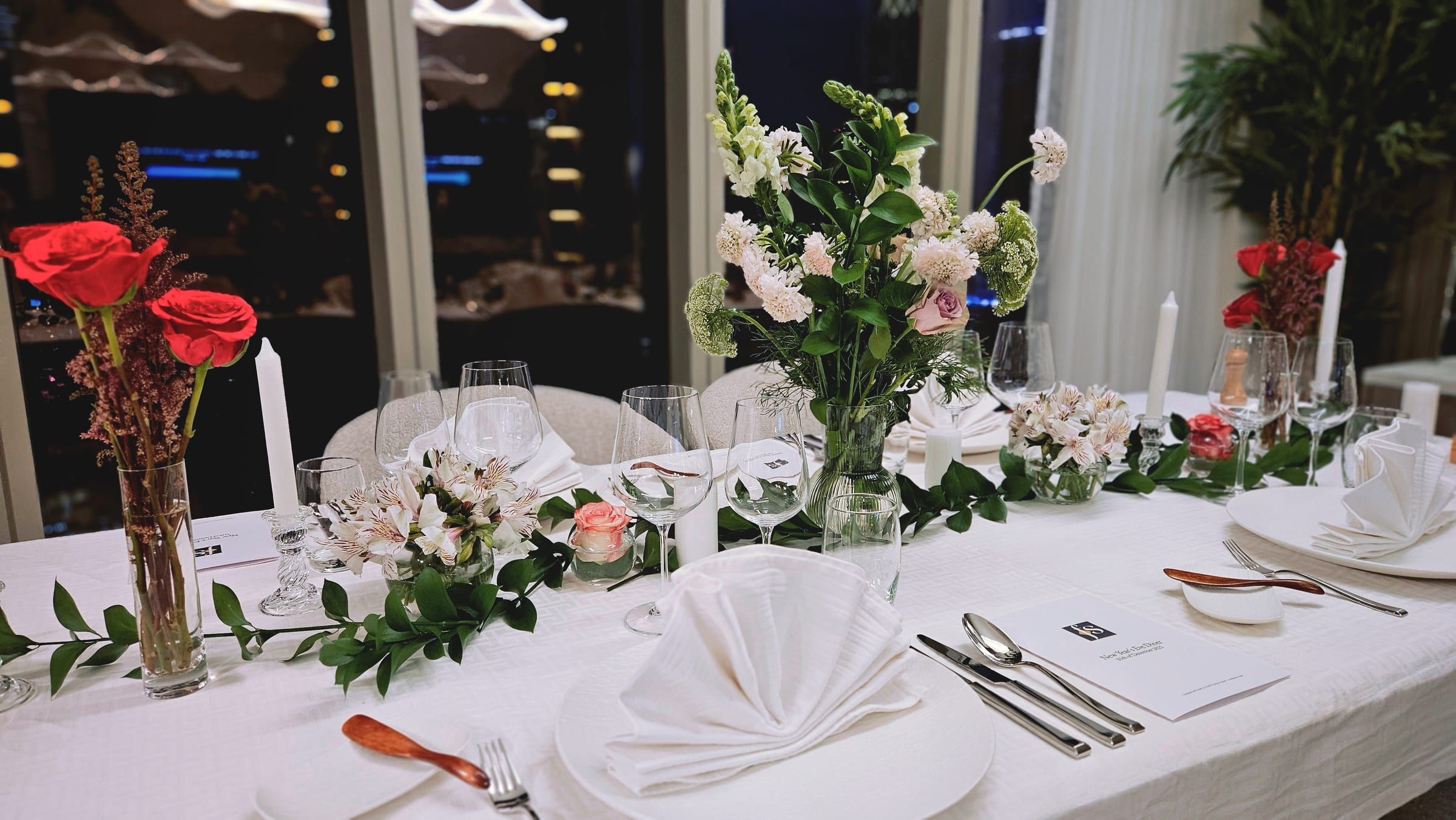 A long Dubai table dressed for the evening, the city lights beyond the glass.
