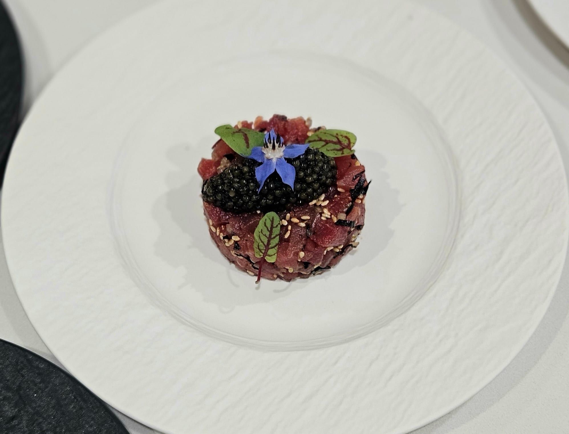 A tartare crowned with a single edible flower, plated by Chef François Savin in Dubai.
