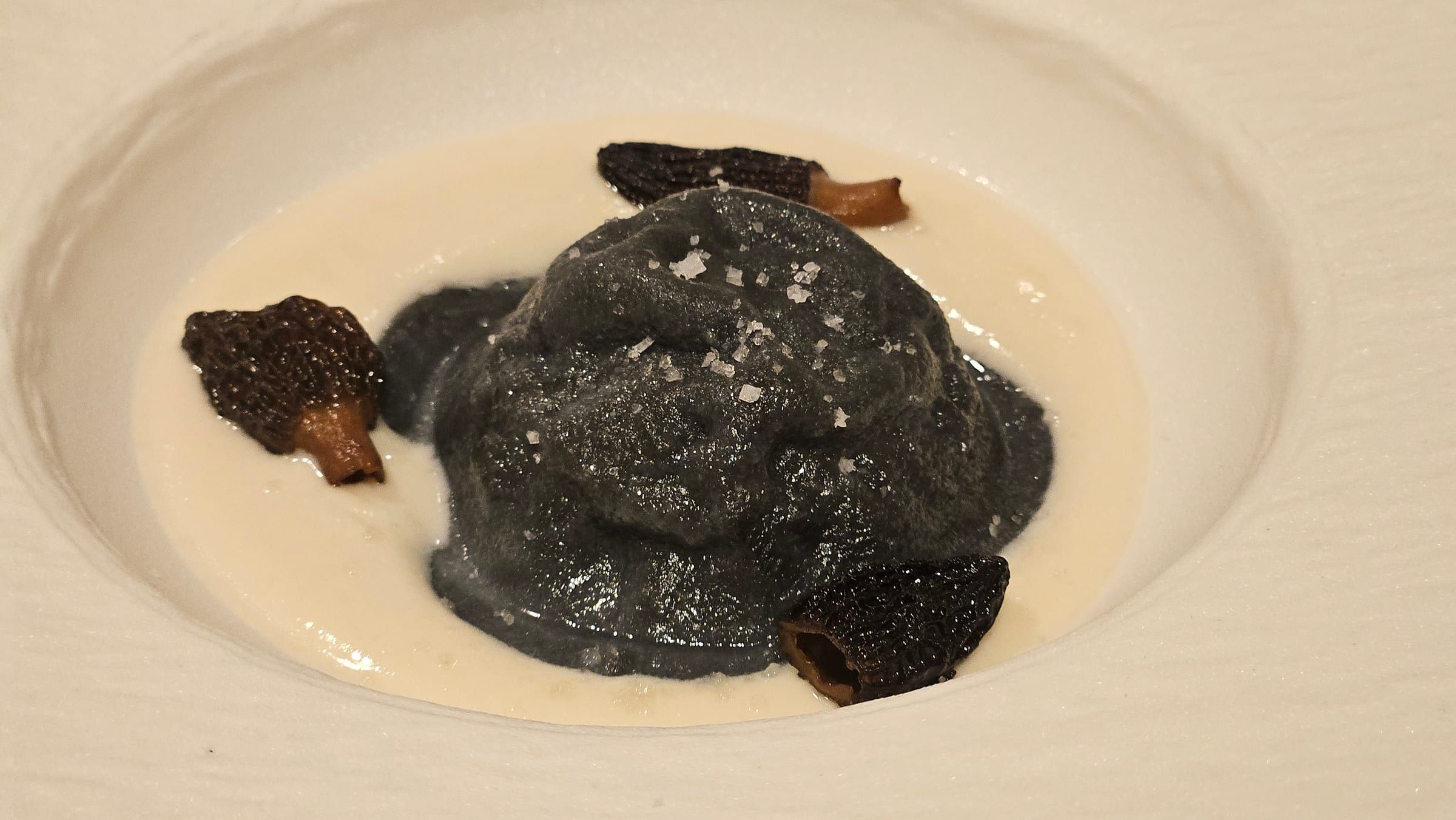 A refined dark quenelle plated on white porcelain.