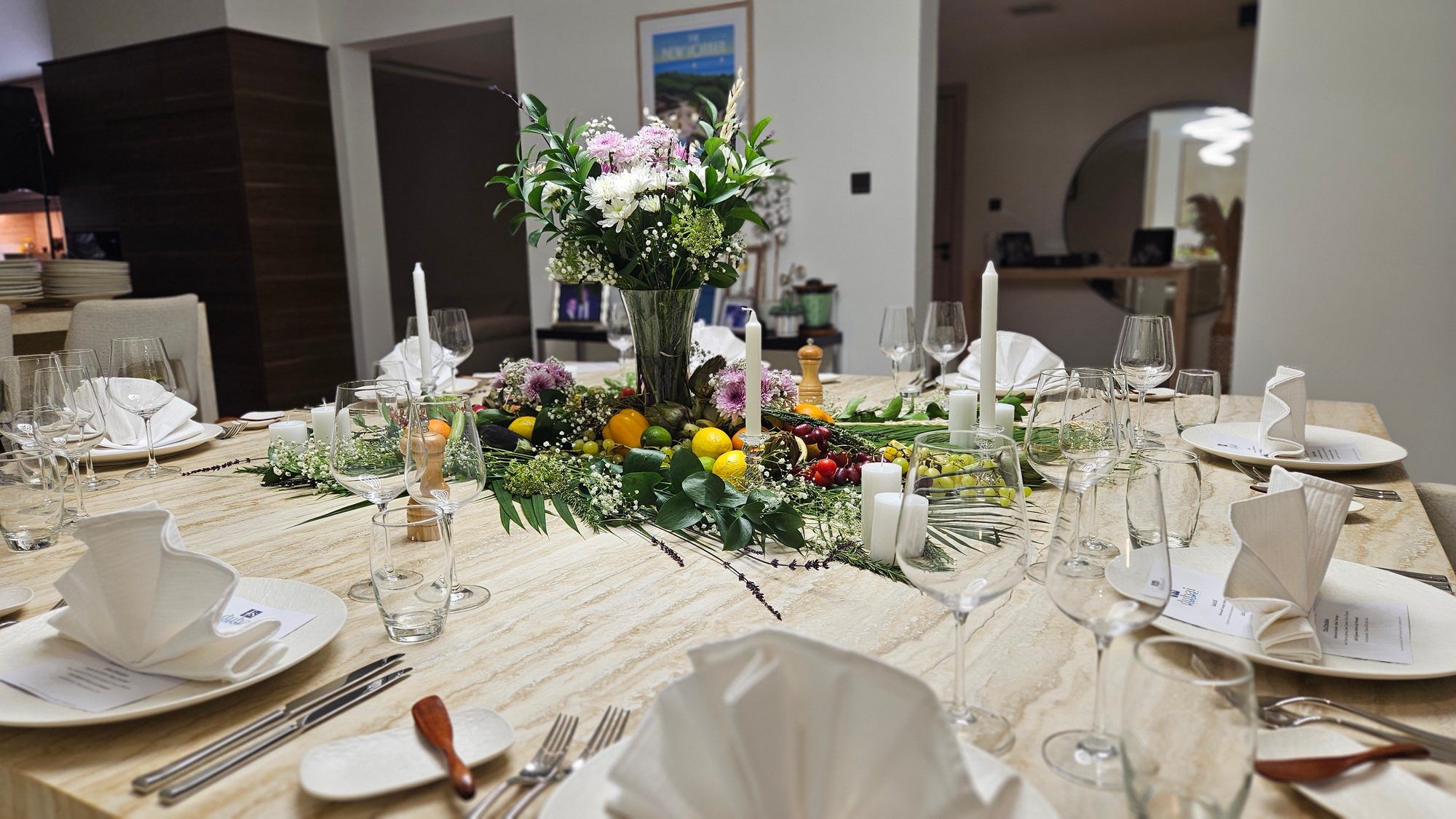 Une table dressée en lin blanc et fleurs, prête pour une soirée devant les lumières de Dubaï.
