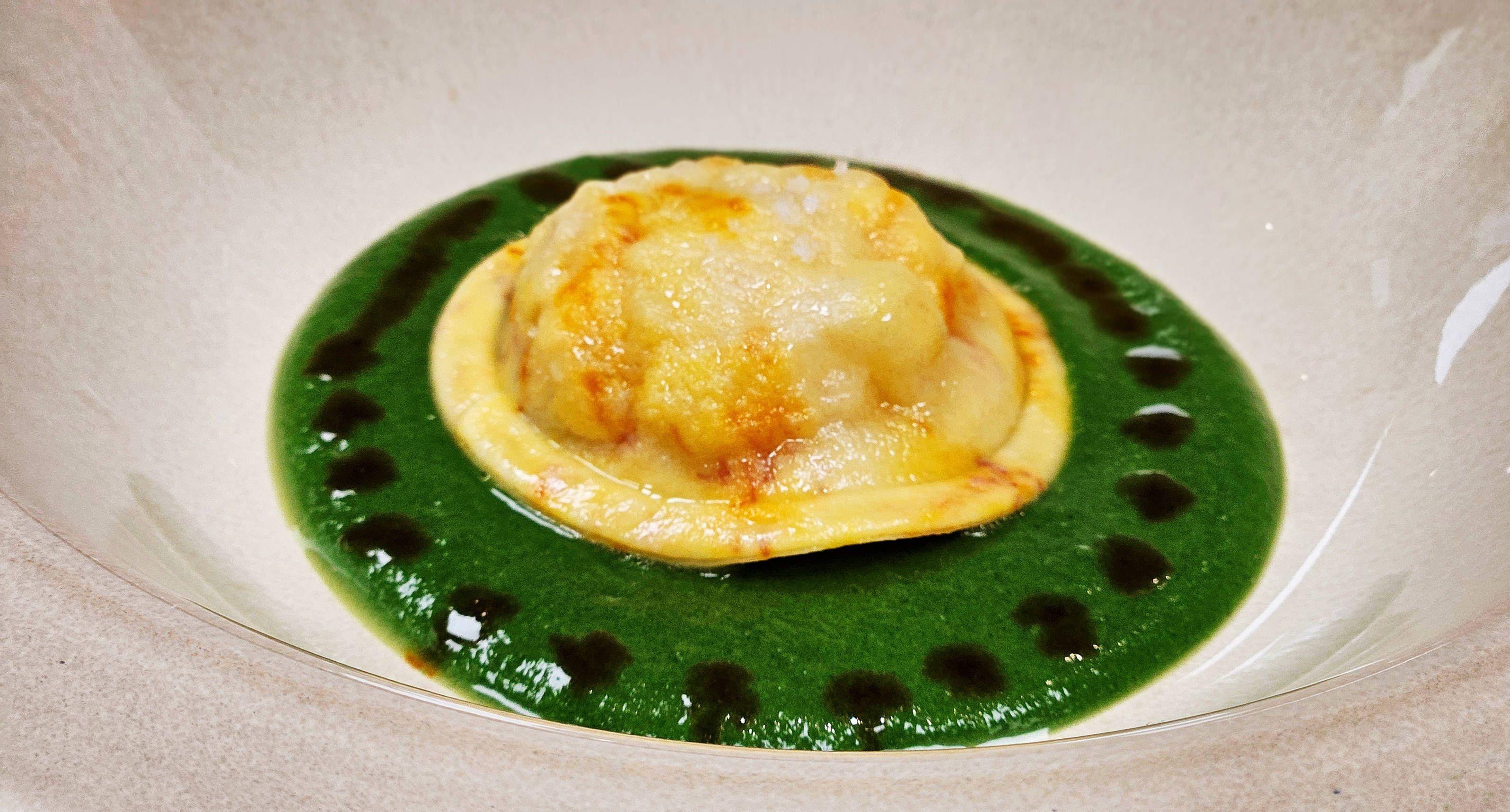Lobster raviolo on a green-herb sauce.