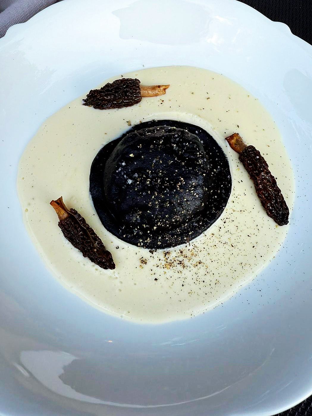 Squid-ink raviolo on a cream of morels.
