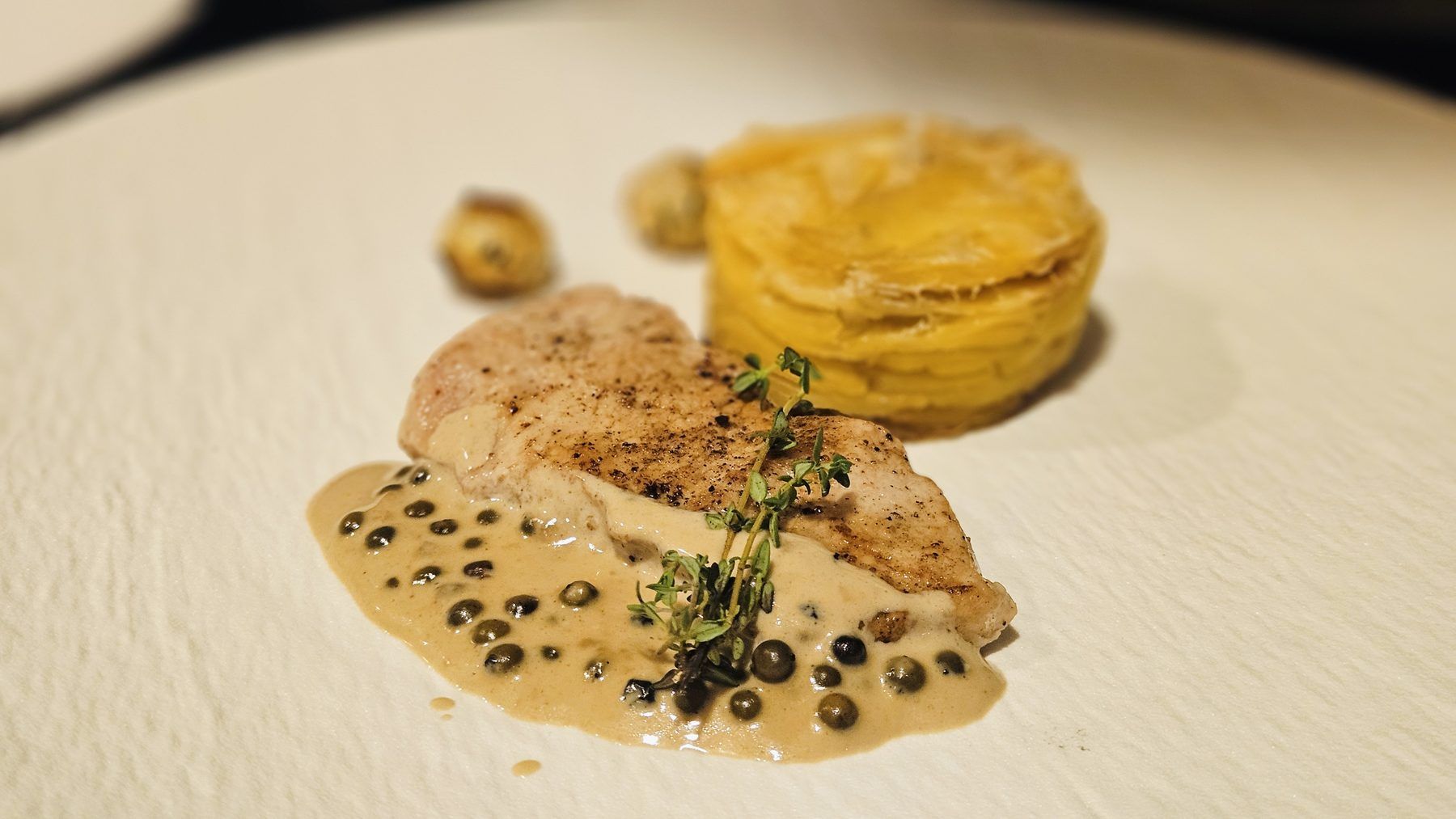 Poultry breast on a peppercorn sauce with a golden potato gratin.