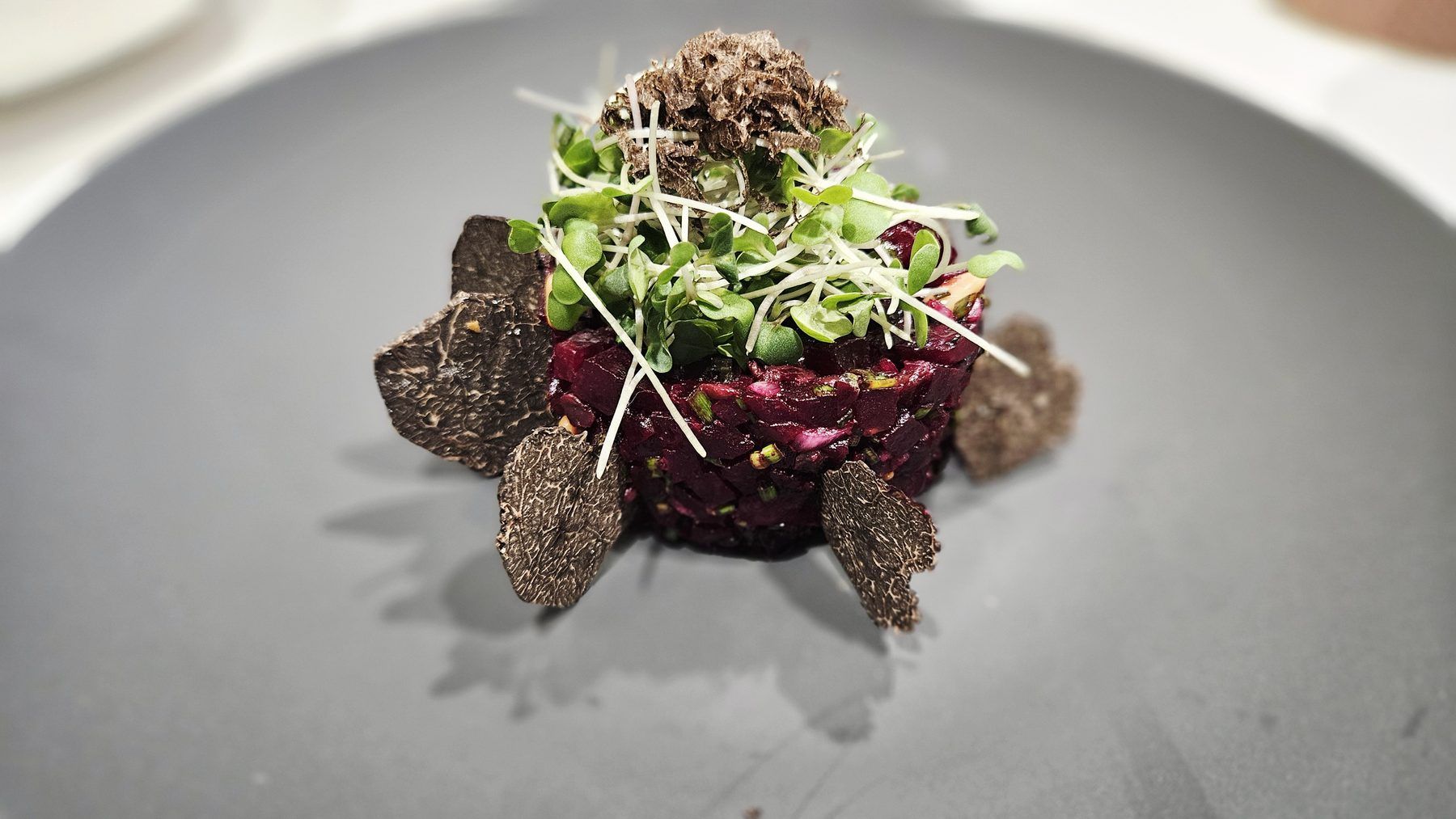 Beetroot tartare topped with shaved truffle and young shoots.