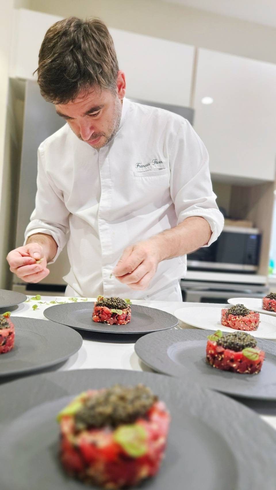 The chef plating tartare starters in series.