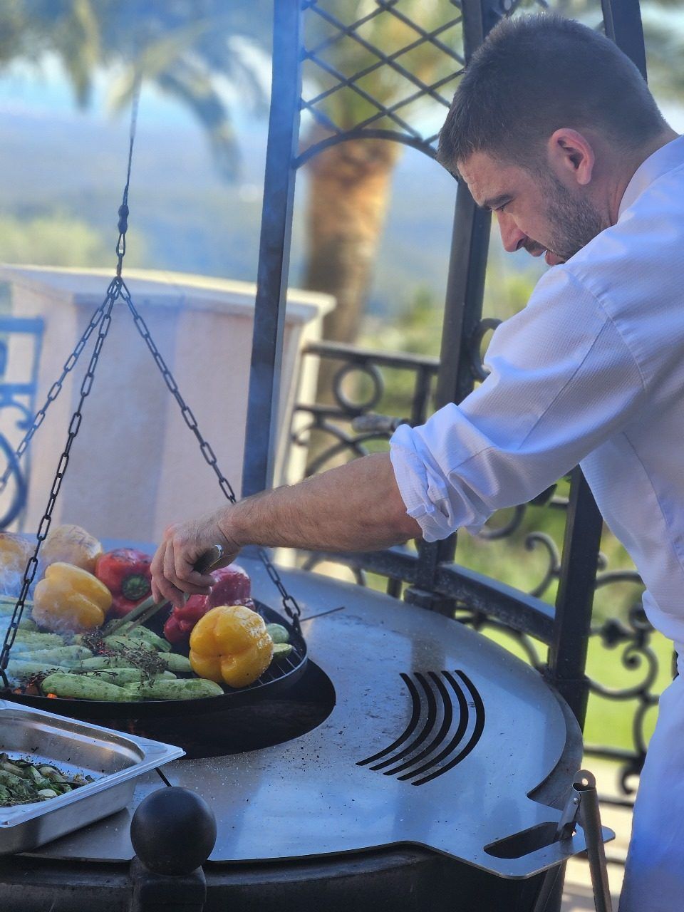 The chef at the outdoor grill with market vegetables.