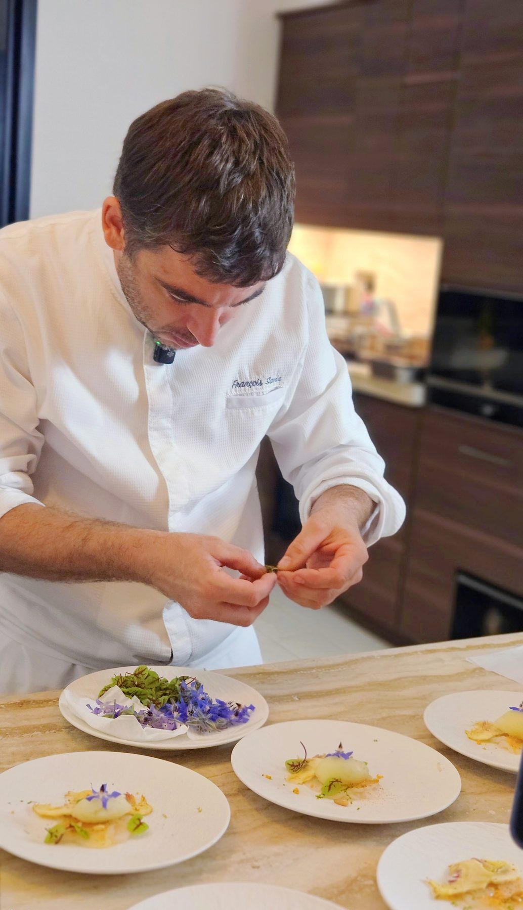 The chef plating a flowered first course in series.
