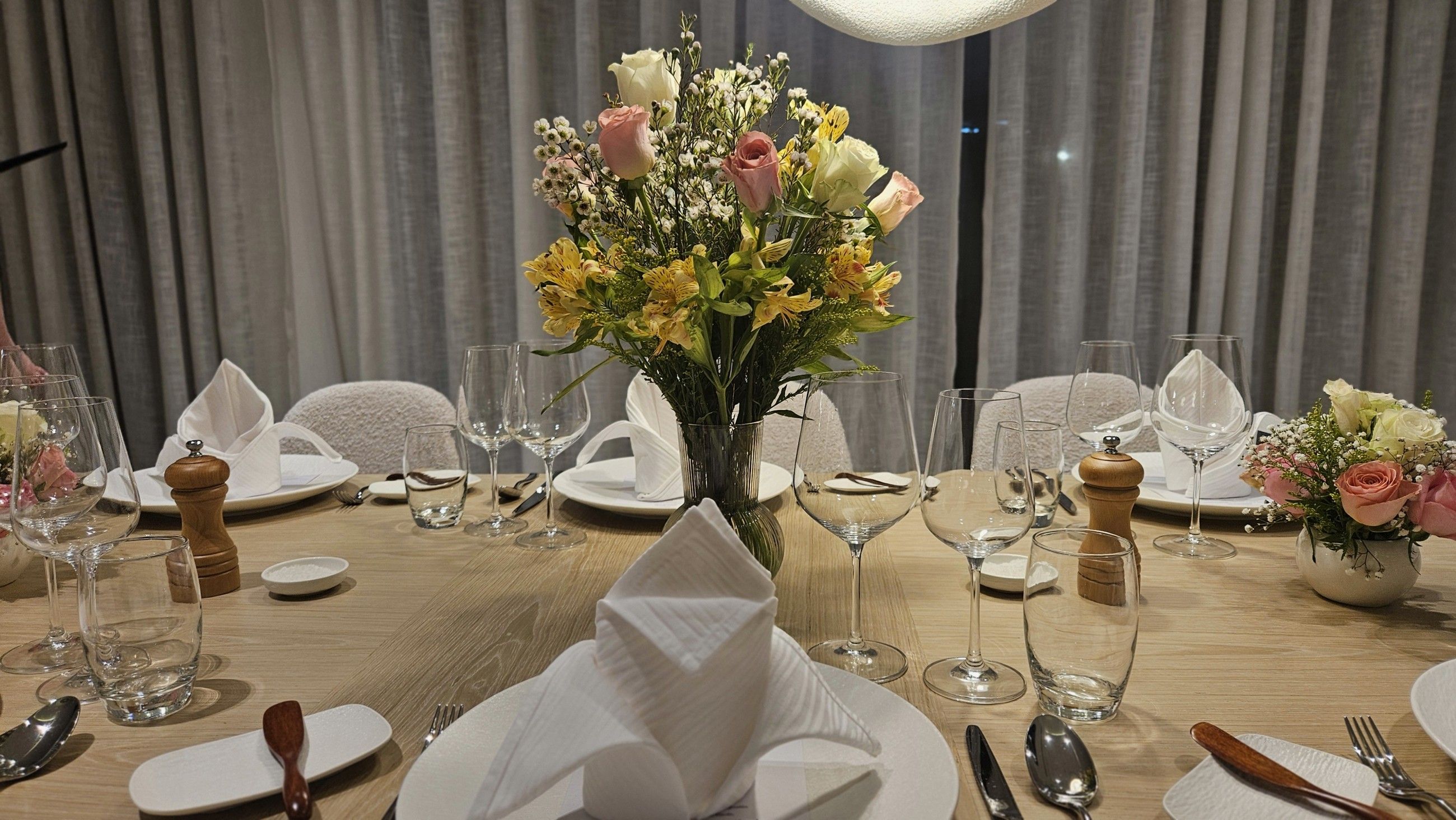 Round table set with spring roses and folded napkins.