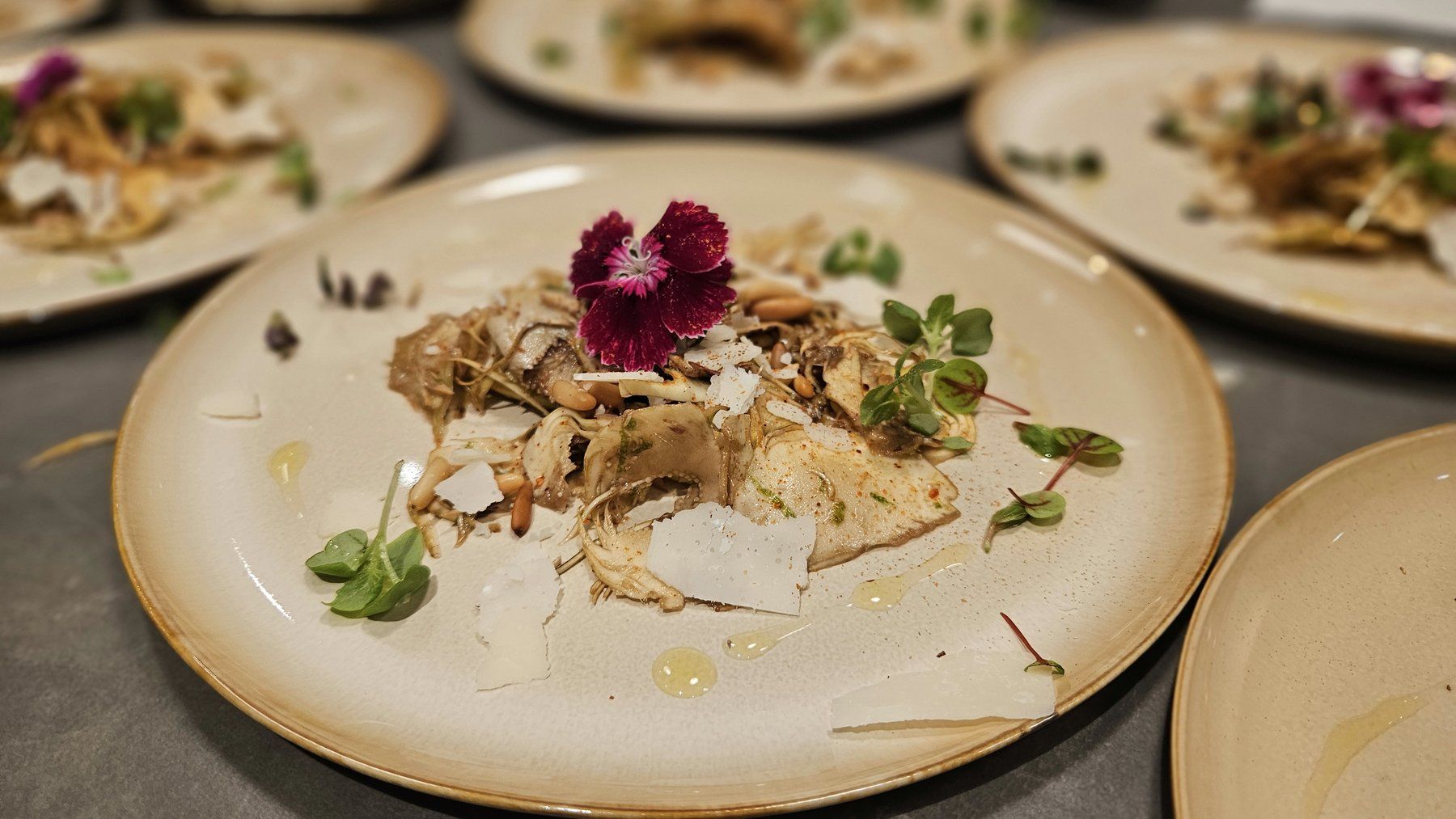 Fish course with parmesan and edible flowers, plated in series.